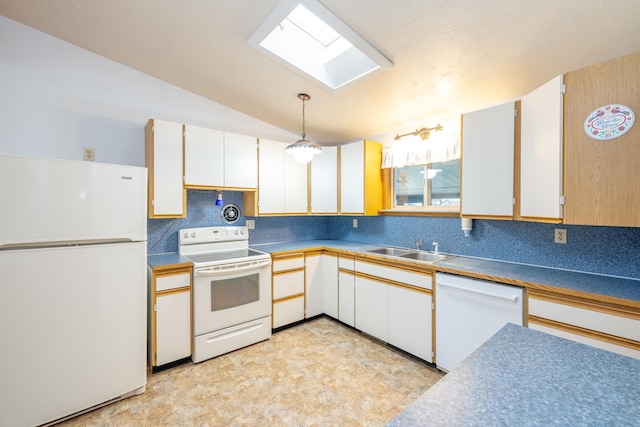 kitchen featuring vaulted ceiling with skylight, white appliances, white cabinets, a sink, and decorative light fixtures