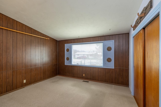 carpeted spare room with wood walls and visible vents