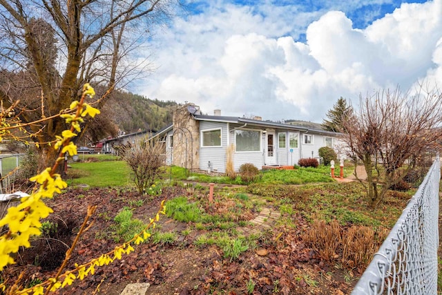 view of side of home with a lawn, fence, and a chimney