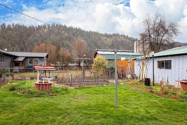 view of yard featuring a mountain view, a vegetable garden, and fence