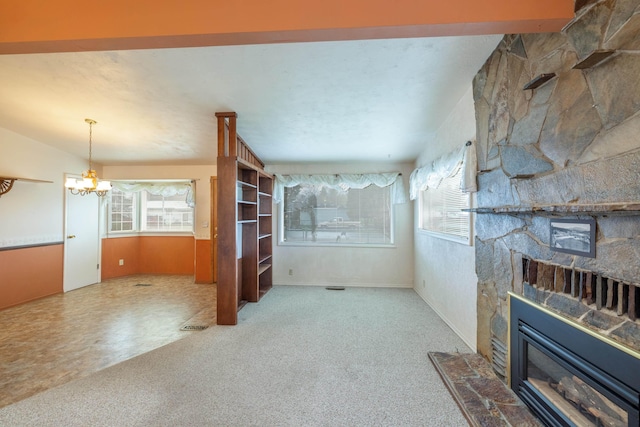 unfurnished living room with a fireplace, plenty of natural light, and an inviting chandelier