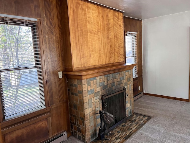 unfurnished living room featuring baseboard heating, carpet flooring, a brick fireplace, and plenty of natural light