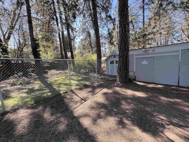 view of yard with a storage unit, fence, and an outbuilding