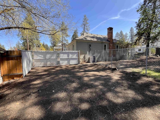 back of property with a gate, fence, and a chimney