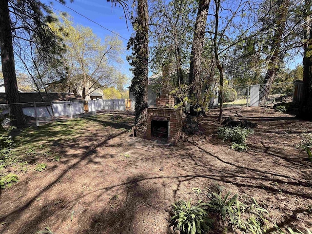 view of yard with an outdoor fireplace and a fenced backyard