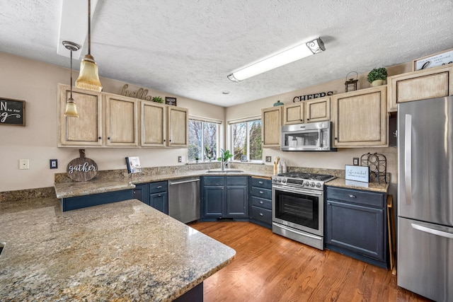 kitchen featuring a sink, appliances with stainless steel finishes, blue cabinetry, and a textured ceiling