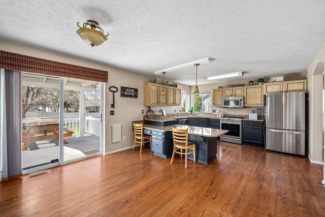 kitchen featuring visible vents, a sink, a kitchen breakfast bar, a textured ceiling, and stainless steel appliances
