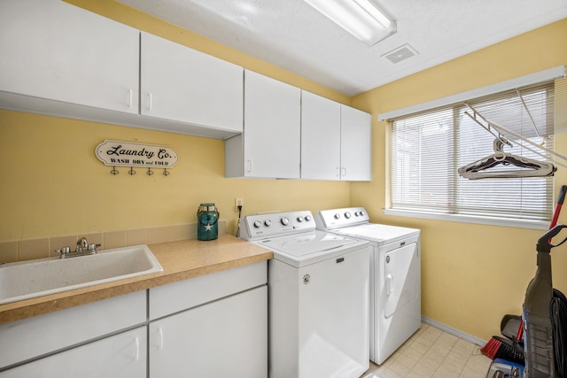 washroom featuring visible vents, baseboards, a sink, cabinet space, and washing machine and dryer