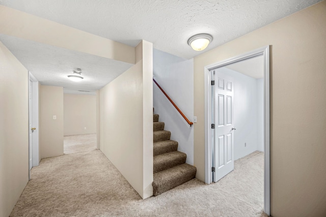 stairs featuring carpet flooring and a textured ceiling