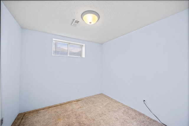 spare room featuring carpet floors, visible vents, and a textured ceiling