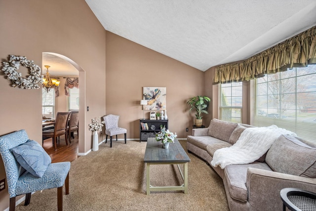 carpeted living area featuring a wealth of natural light, arched walkways, an inviting chandelier, and a textured ceiling