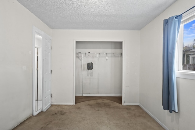 interior space with a textured ceiling, carpet, a closet, and baseboards