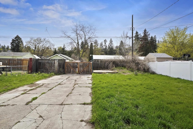 view of yard featuring a gate, fence private yard, and concrete driveway