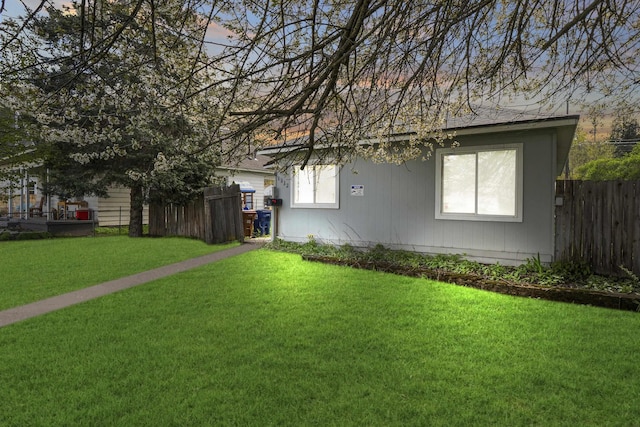 view of side of home featuring a lawn and fence