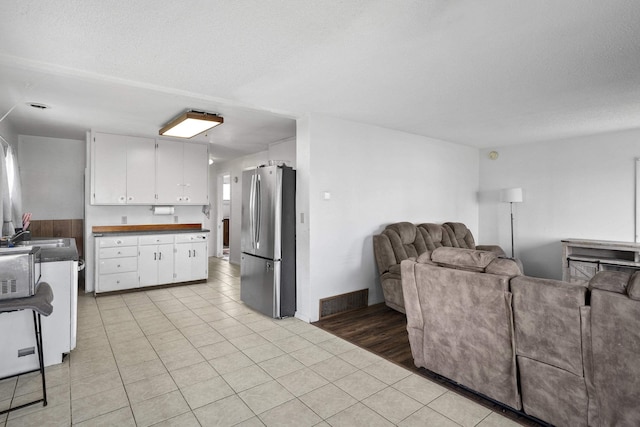living area featuring light tile patterned flooring, a textured ceiling, and visible vents