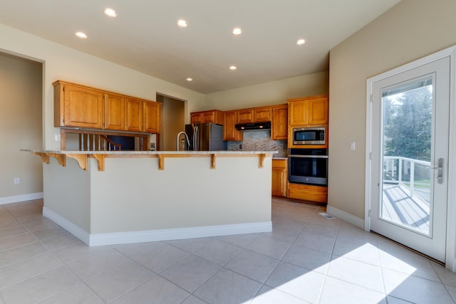 6519 W Kitsap Dr, Spokane, WA 99208 - kitchen featuring decorative backsplash, appliances with stainless steel finishes, under cabinet range hood, a kitchen bar, and recessed lighting
