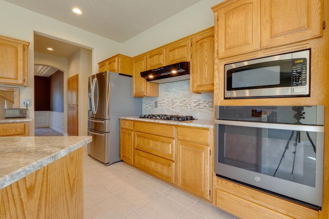 6519 W Kitsap Dr, Spokane, WA 99208 - kitchen with under cabinet range hood, light countertops, arched walkways, wainscoting, and appliances with stainless steel finishes