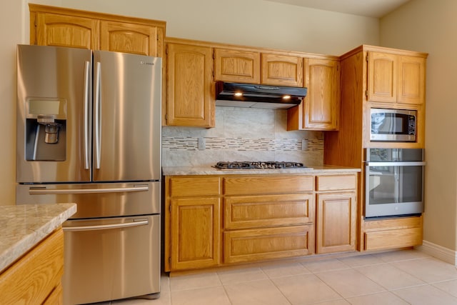 6519 W Kitsap Dr, Spokane, WA 99208 - kitchen with decorative backsplash, light tile patterned floors, stainless steel appliances, under cabinet range hood, and baseboards