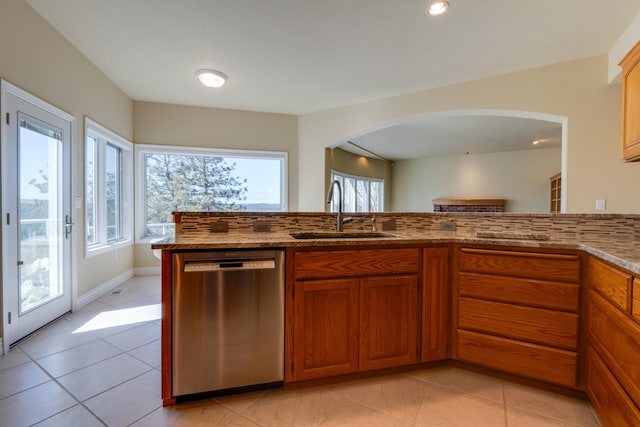 6519 W Kitsap Dr, Spokane, WA 99208 - kitchen with light stone countertops, arched walkways, brown cabinetry, dishwasher, and a sink