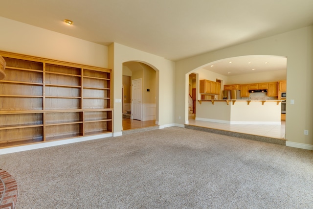 6519 W Kitsap Dr, Spokane, WA 99208 - unfurnished living room with baseboards, arched walkways, and light carpet