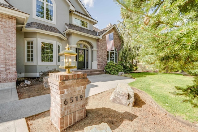 6519 W Kitsap Dr, Spokane, WA 99208 - view of exterior entry featuring stucco siding, a yard, and brick siding