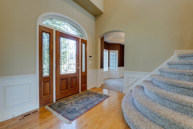 6519 W Kitsap Dr, Spokane, WA 99208 - foyer entrance featuring stairs, visible vents, arched walkways, wainscoting, and wood finished floors