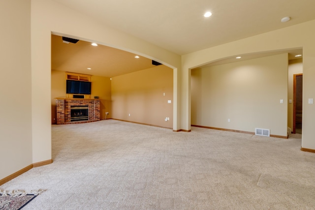 6519 W Kitsap Dr, Spokane, WA 99208 - unfurnished living room featuring light colored carpet, visible vents, arched walkways, recessed lighting, and a fireplace