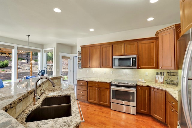6610 S Springview St, Spokane, WA 99224 - kitchen with stainless steel appliances, brown cabinetry, light wood finished floors, tasteful backsplash, and recessed lighting