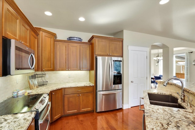 6610 S Springview St, Spokane, WA 99224 - kitchen featuring appliances with stainless steel finishes, brown cabinetry, arched walkways, wood finished floors, and recessed lighting