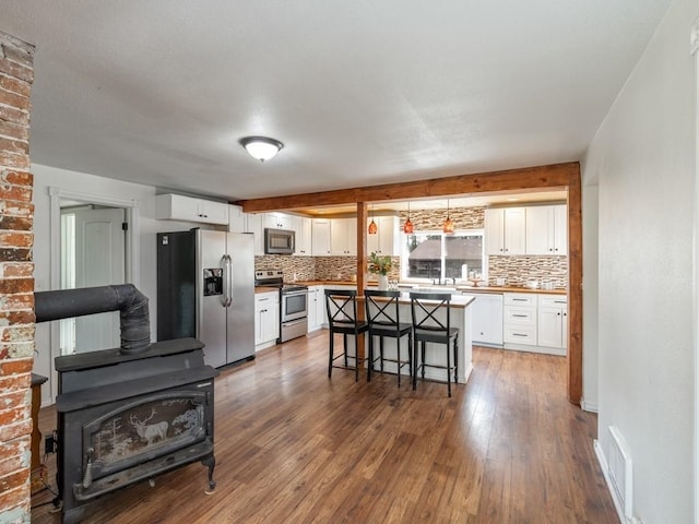 kitchen featuring hardwood / wood-style floors, appliances with stainless steel finishes, backsplash, and white cabinets