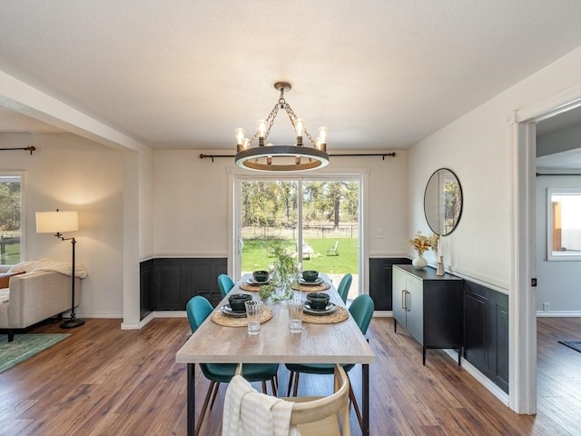dining space with a chandelier, plenty of natural light, and a wainscoted wall