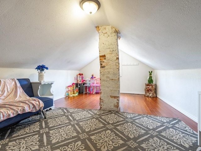 additional living space featuring wood finished floors, vaulted ceiling, and a textured ceiling
