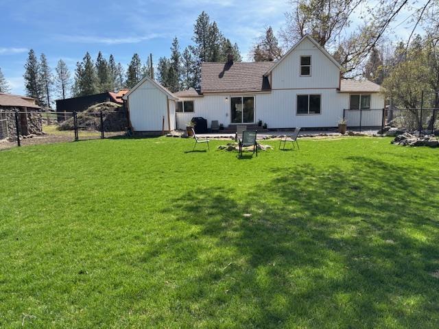 rear view of house with fence and a lawn