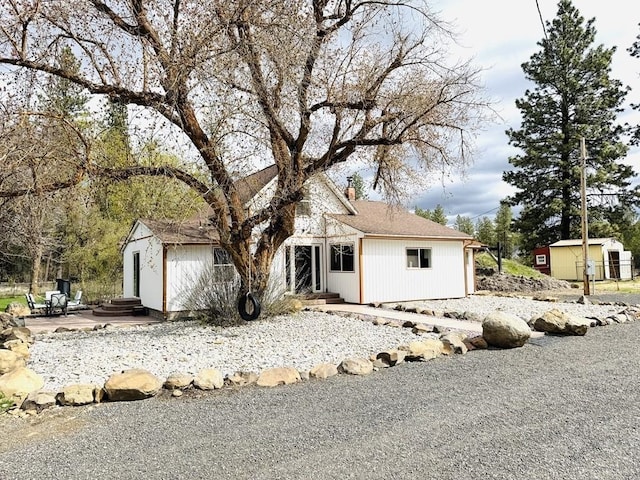 view of front of home featuring entry steps, a patio area, and a chimney