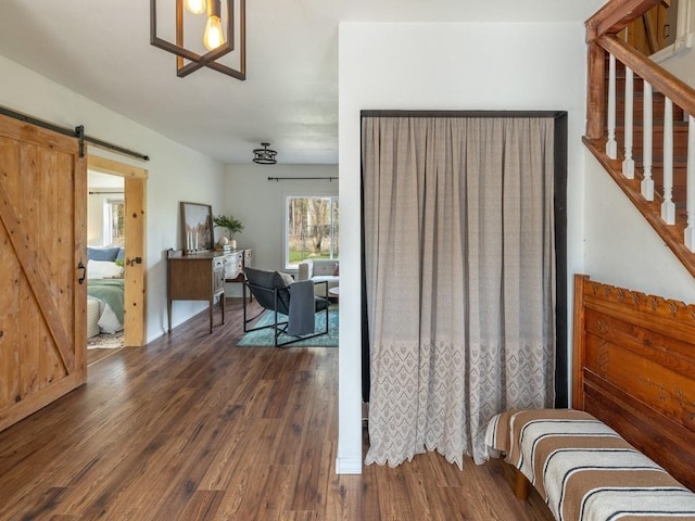 bedroom with a barn door and wood finished floors