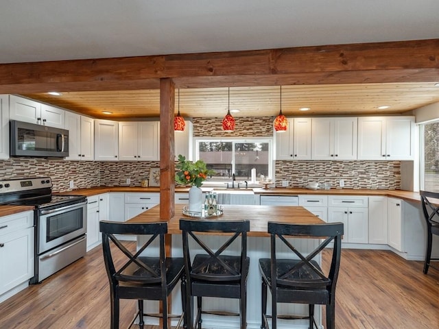 kitchen featuring stainless steel electric range oven, wood finished floors, and wooden counters