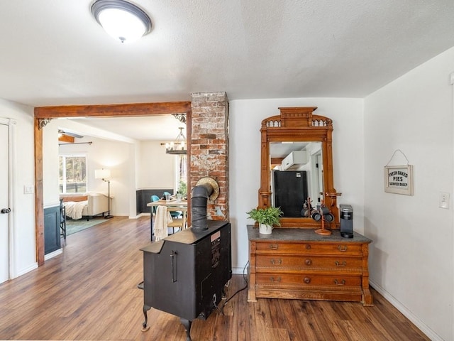 living room with a wood stove, baseboards, an inviting chandelier, and wood finished floors