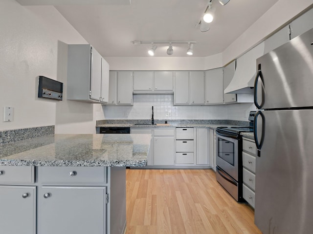kitchen with a sink, light wood finished floors, gray cabinetry, light stone countertops, and stainless steel appliances