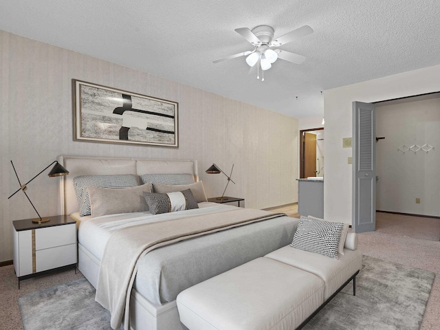 bedroom featuring a textured ceiling, light colored carpet, baseboards, and a ceiling fan