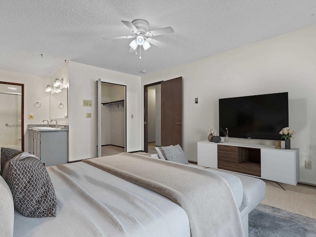 bedroom featuring ensuite bath, a textured ceiling, a ceiling fan, light colored carpet, and a sink