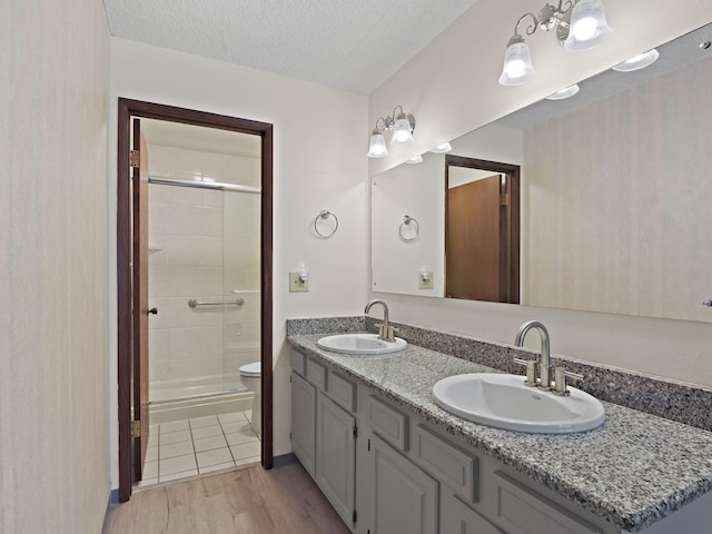 bathroom featuring a shower stall, wood finished floors, a sink, and toilet