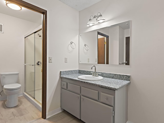 full bath featuring vanity, baseboards, toilet, a shower stall, and wood finished floors