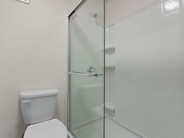 full bathroom featuring a shower stall and toilet