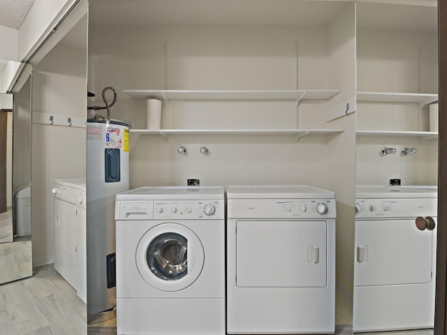 washroom featuring water heater, separate washer and dryer, laundry area, and light wood finished floors