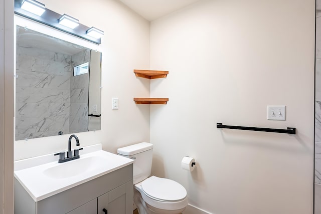 bathroom with toilet, vanity, and baseboards