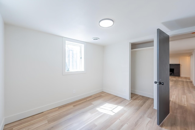 unfurnished bedroom with visible vents, baseboards, light wood finished floors, and a fireplace