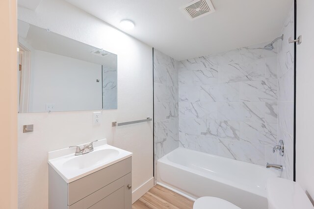 full bath featuring vanity, visible vents, toilet, wood finished floors, and washtub / shower combination