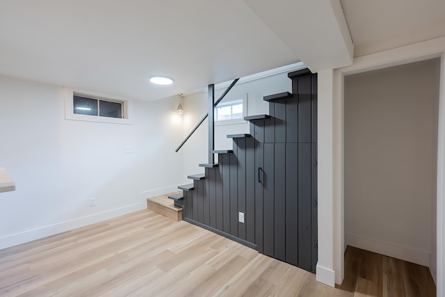 below grade area with light wood-style flooring, baseboards, and stairs