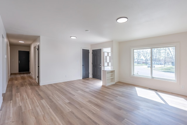 spare room with baseboards, light wood finished floors, and recessed lighting