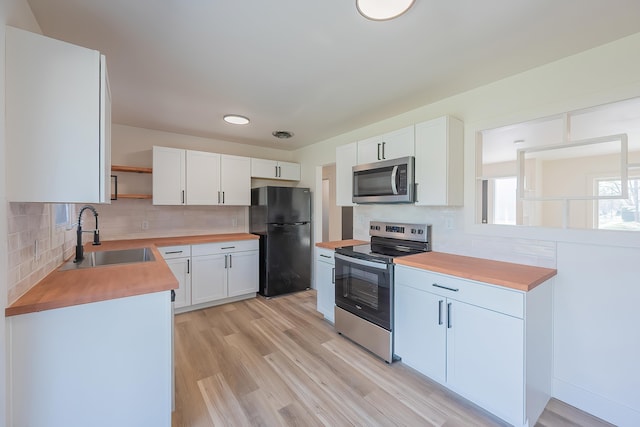 kitchen featuring tasteful backsplash, open shelves, a sink, wooden counters, and appliances with stainless steel finishes